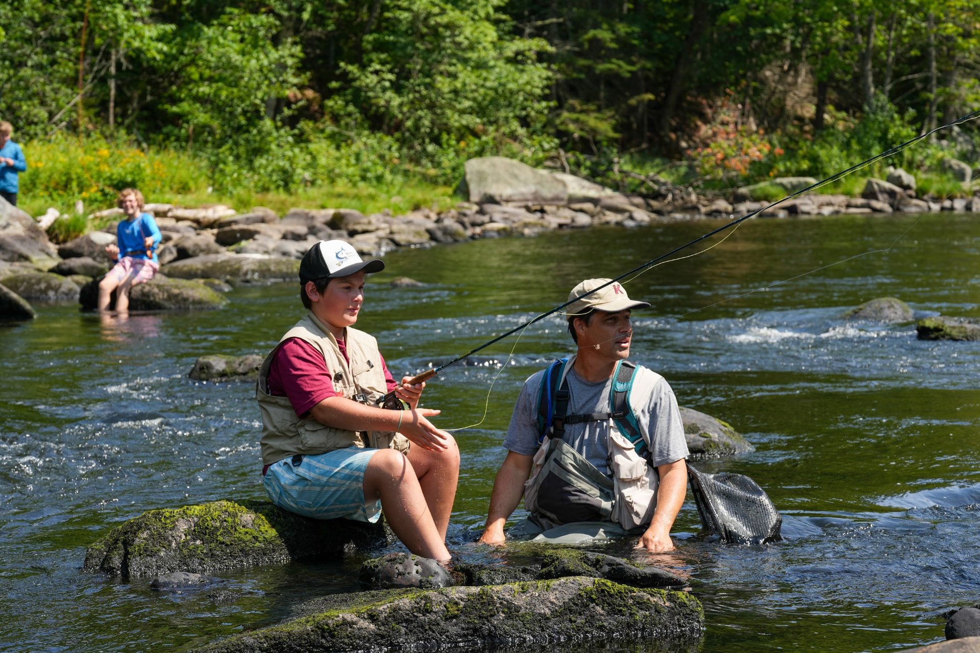 Kevin Bonasera teaching a camper to fly cast in a river