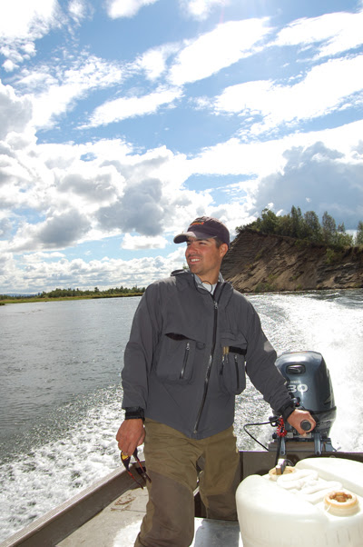 Kevin Bonasera standing at the stern of a river boat, oars in hand