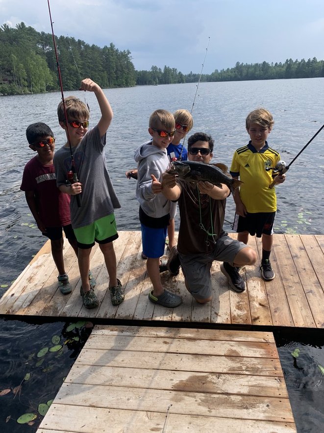 Kevin Bonasera with campers showing a bass caught from the camp dock