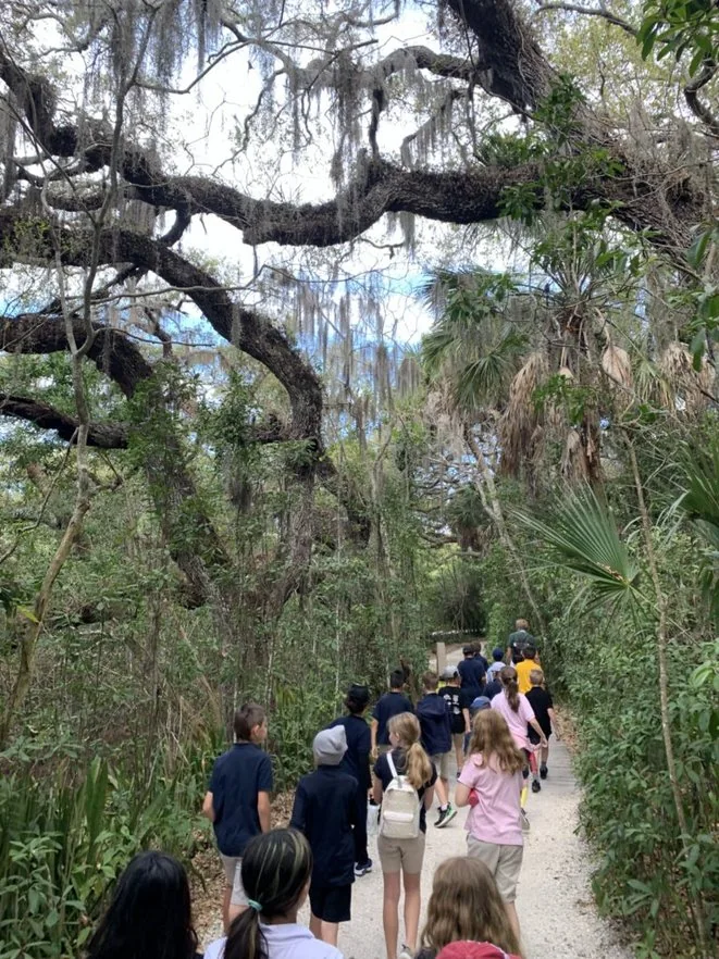 Students walking a shaded nature trail during a Sarasota field trip